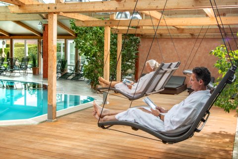 Ein Mann und eine Frau in einem Schaukelstuhl am Pool.