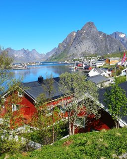 Rote Häuser am Wasser mit Bergen im Hintergrund