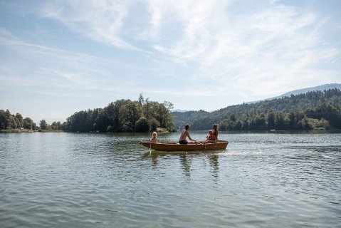 Ruderboot mit Eltern und Kind im Wasser am Reintalersee