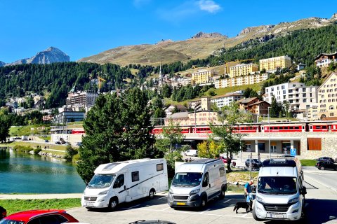 3 Wohnmobile auf einem Stellplatz am Wasser.