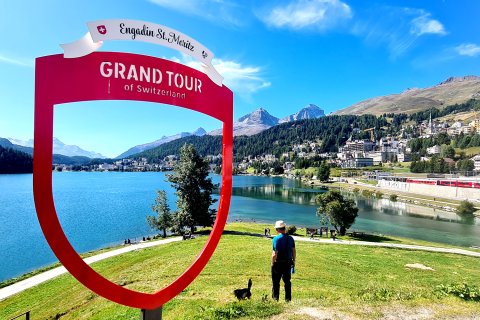 Mann und Hund bei Grand Tour of Switzerland Schild.