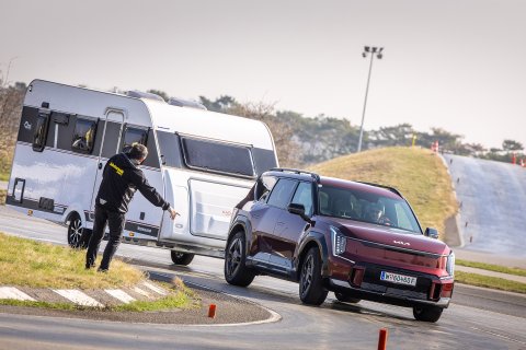 Kia EV9 Elestro-SUV
                           mit Wohnanhänger bei Kurvenfahrt und mit Instruktor