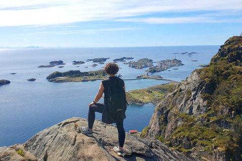 Sabine auf einem Kliff mit das Meer und die Berge im Hintergrund.